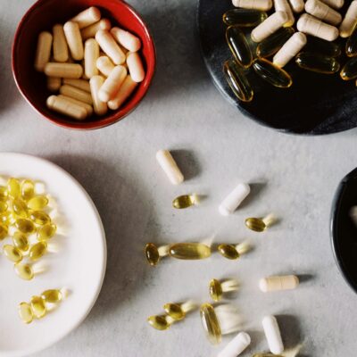 Top view of various types of gelatin coated drugs placed in bowls on stand and between plates on gray tabletop