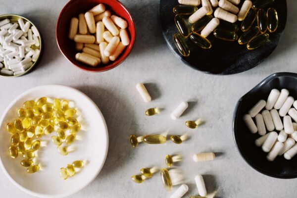 Top view of various types of gelatin coated drugs placed in bowls on stand and between plates on gray tabletop